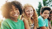 Kids sit and smile during visit to woods while summer vacation.